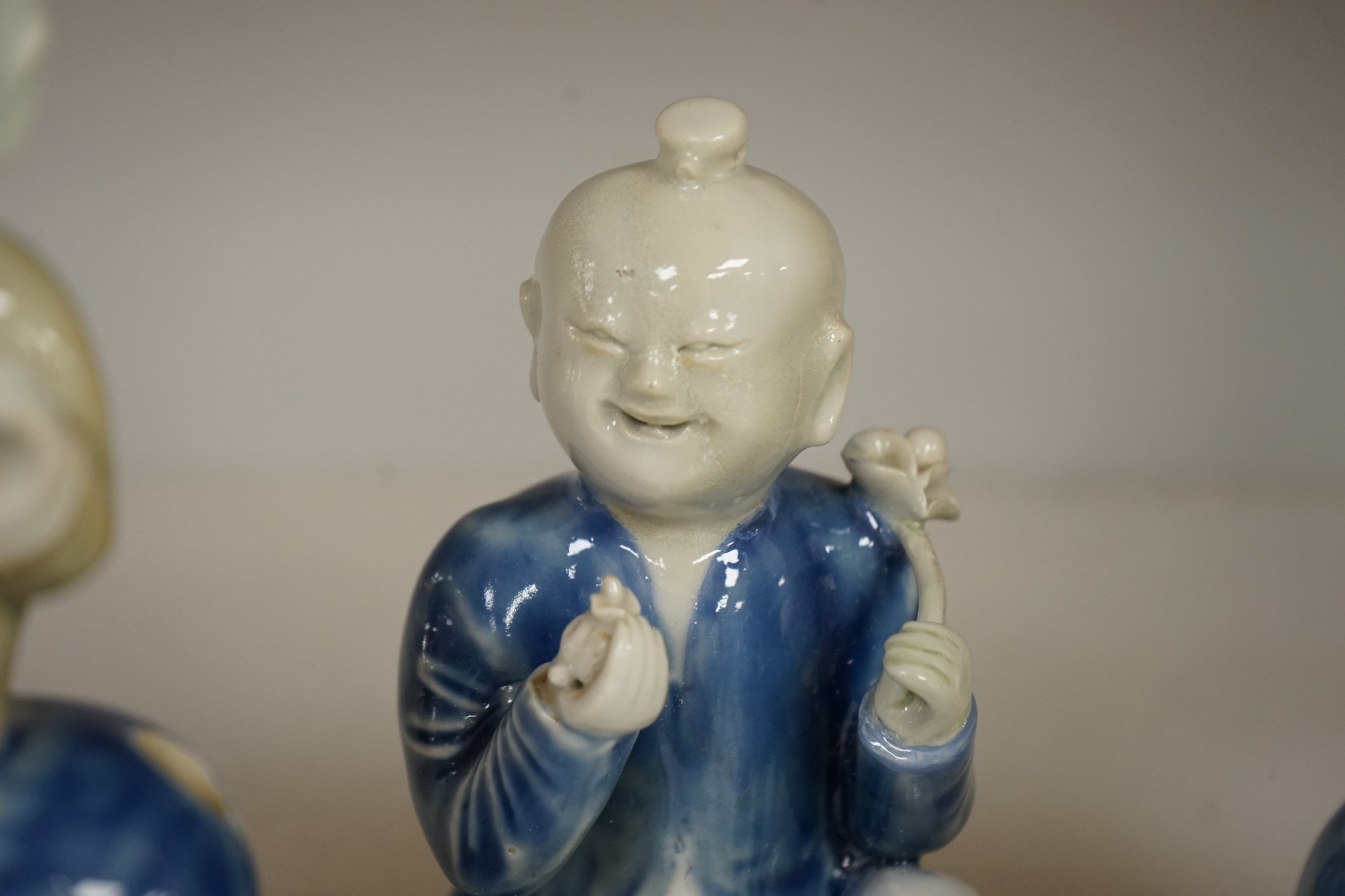 Three Chinese celadon and blue glazed porcelain boy figures, 18th century, largest 20cm high. Condition - fair, all restored